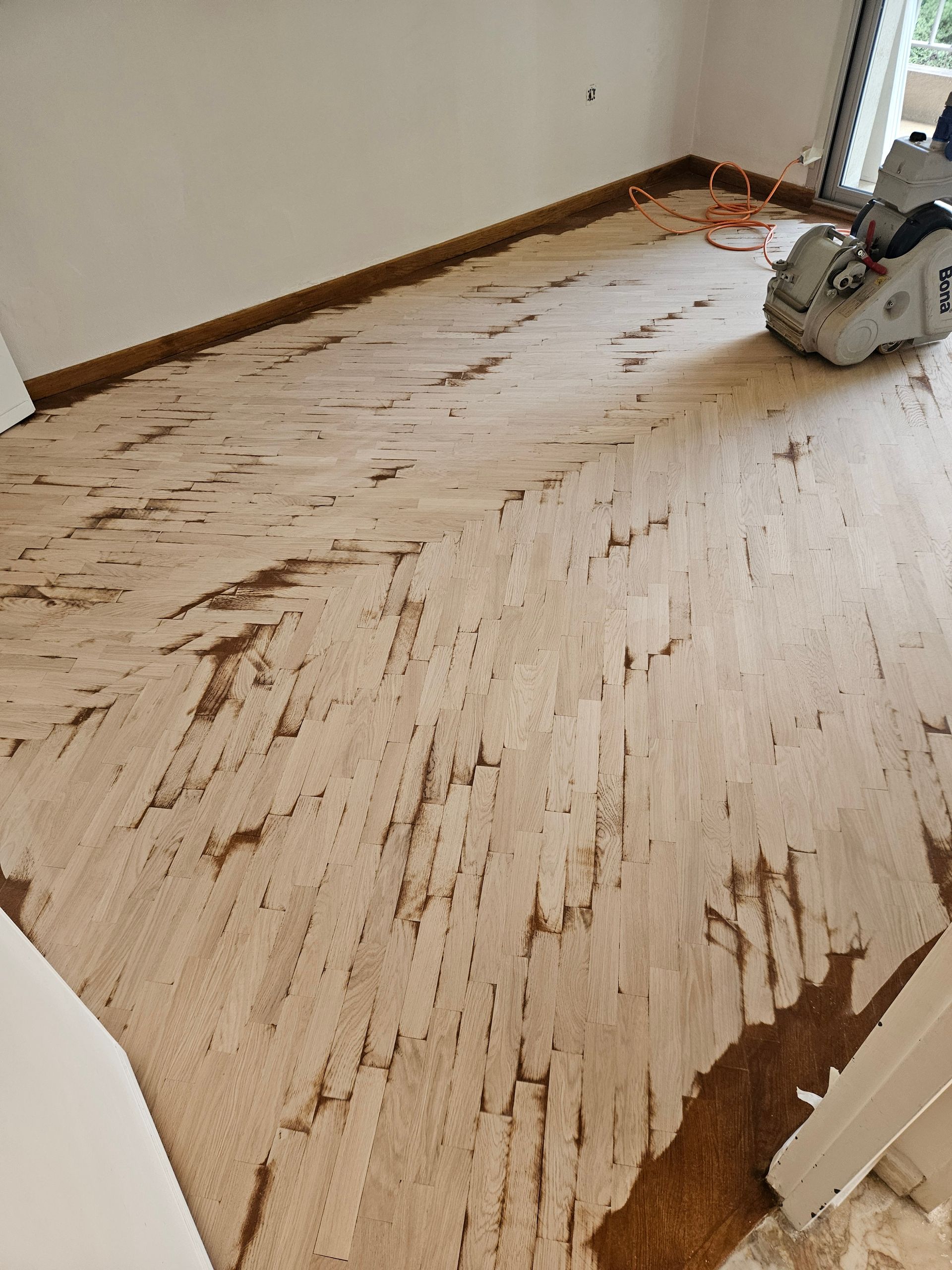 Plancher à chevrons clairs en train d'être poncé