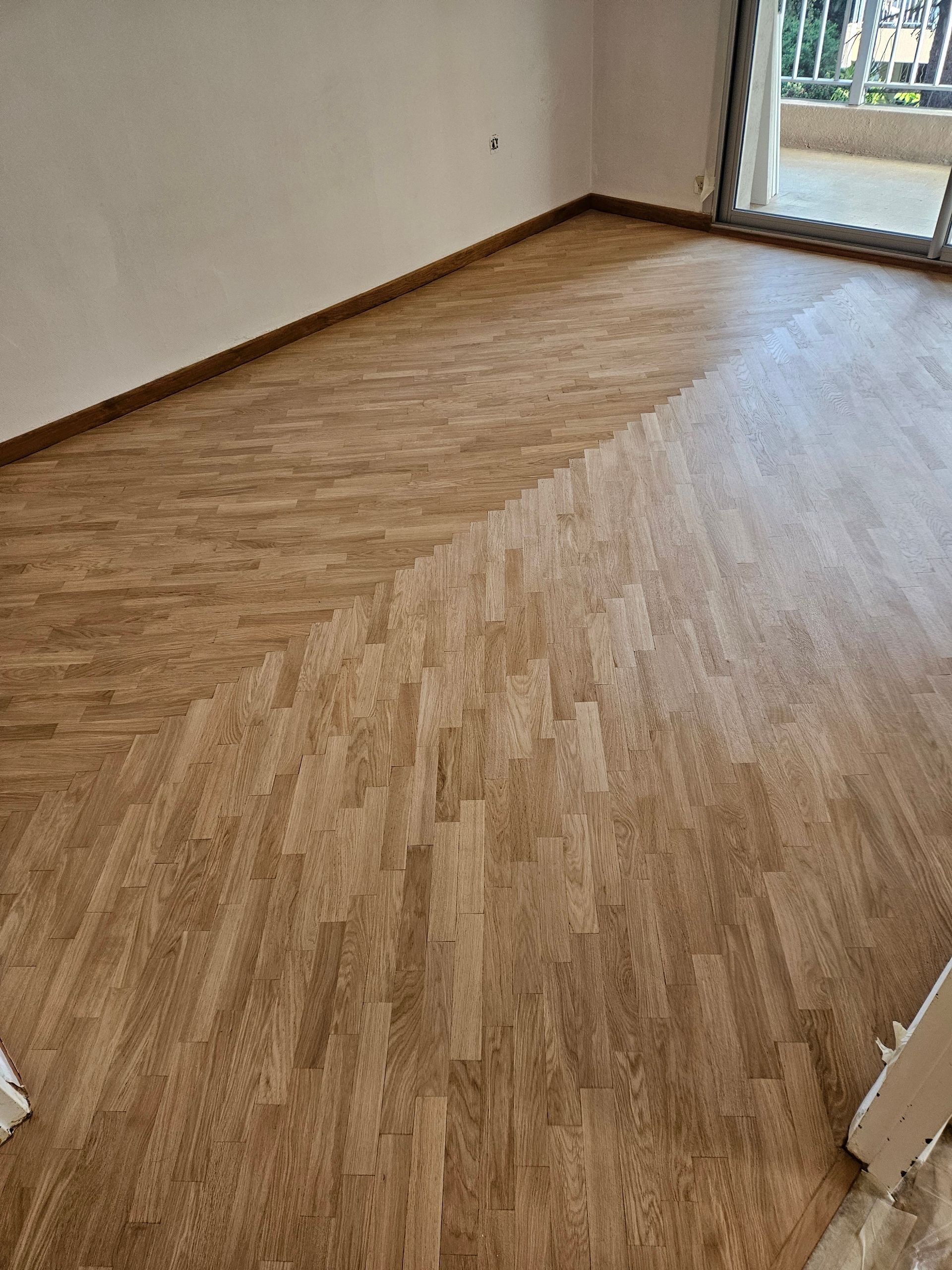 Plancher à chevrons clairs en train d'être poncé