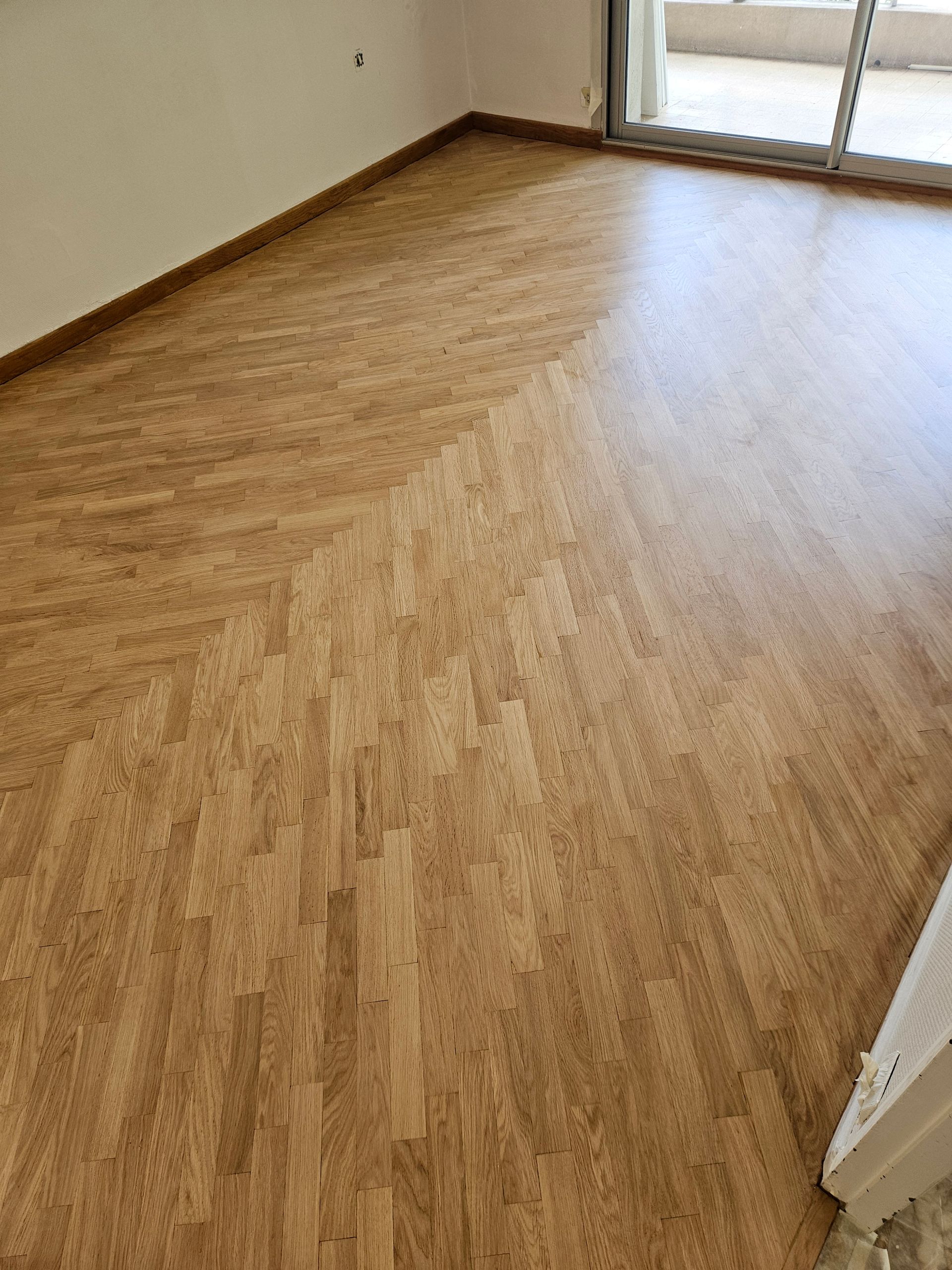 Parquet en grand chevron rénové dans une pièce lumineuse