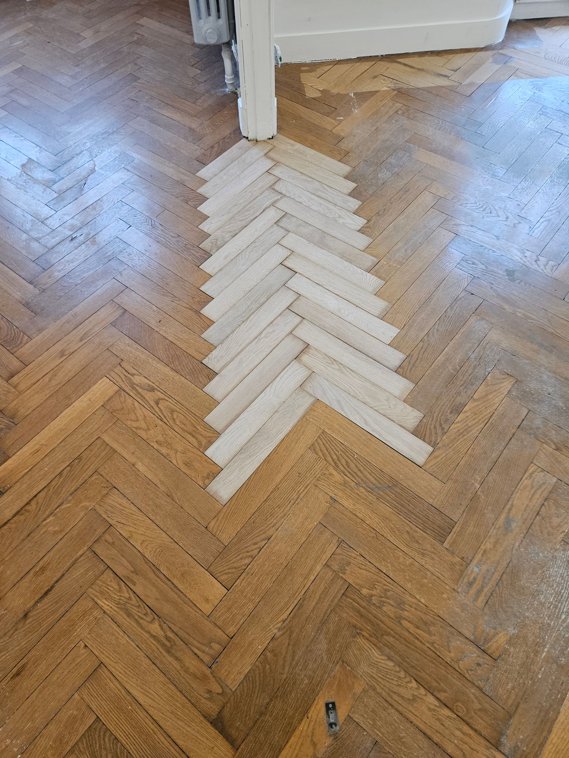 Zone de parquet neuf et blanc au milieu de l'ancien parquet
