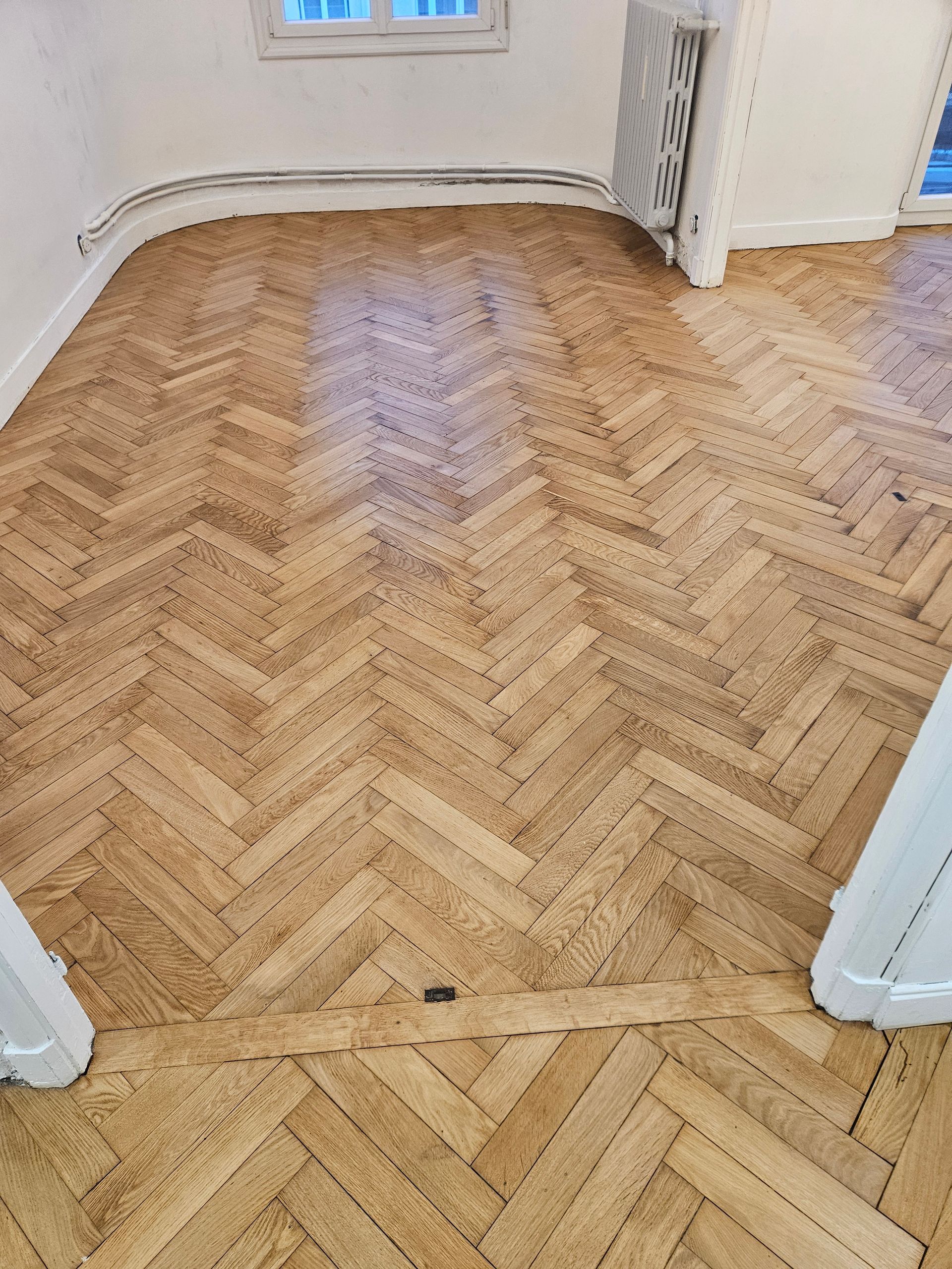 Parquet à chevrons rénové et uniforme dans une pièce lumineuse