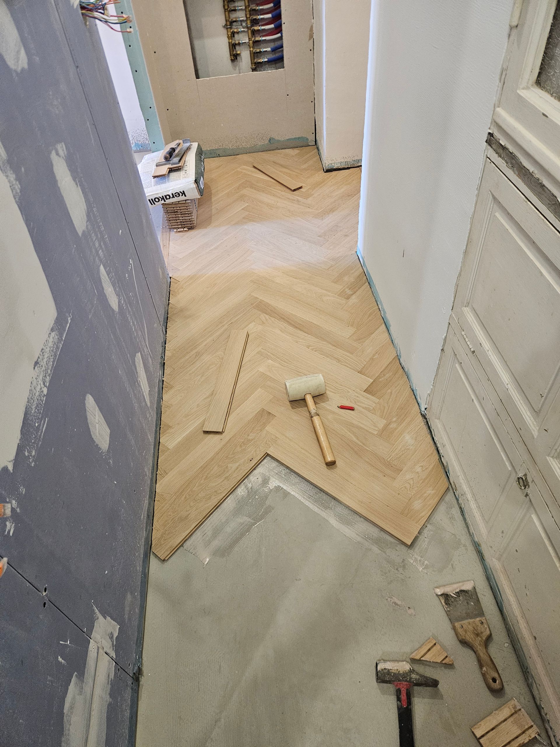 Plancher à bâtons rompus dans un couloir, posé avec un maillet