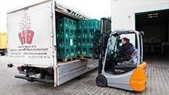 Ein Mann fährt einen Gabelstapler, um Flaschen in einen Lastwagen zu laden.