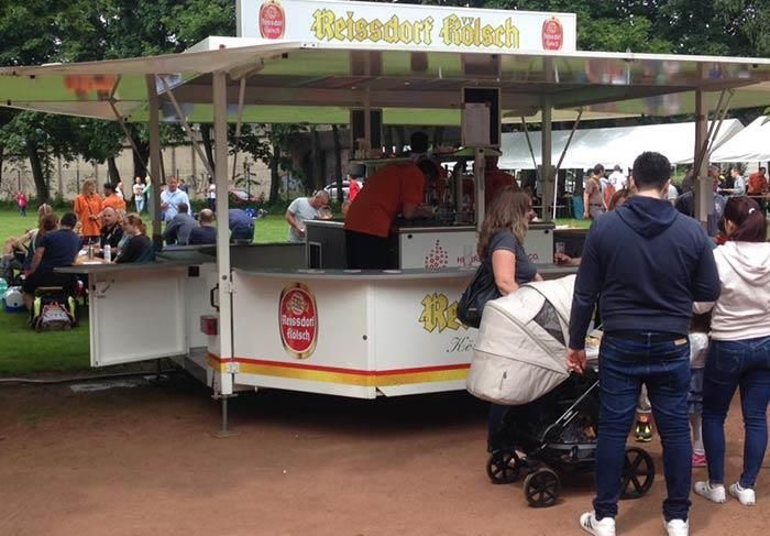 Eine Gruppe von Menschen steht vor einem Imbissstand, auf dem „Fleisch“ steht