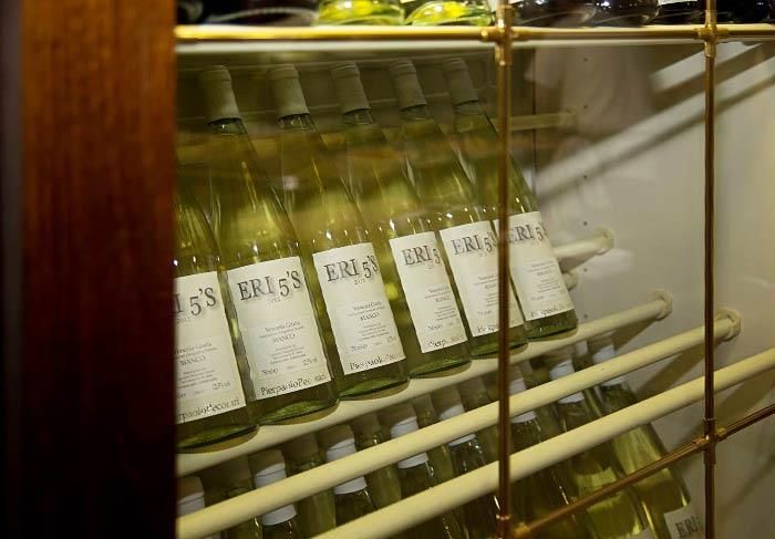 Flaschen Weißwein stehen aufgereiht auf einem Regal