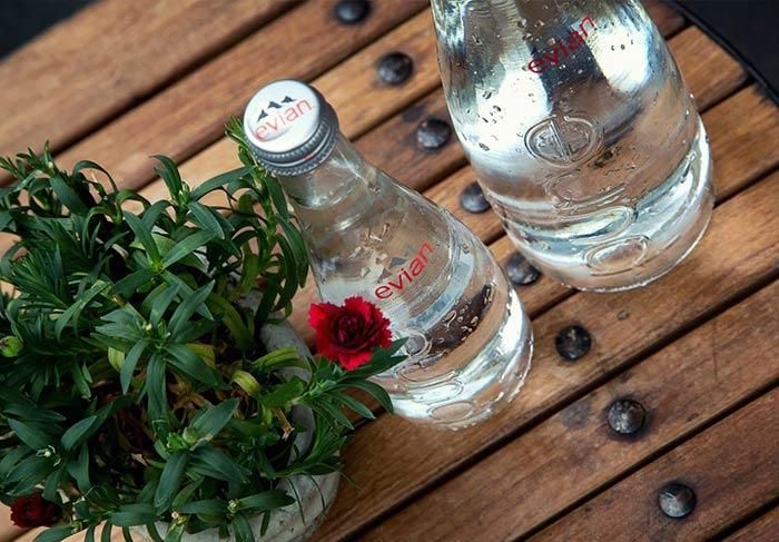 Zwei Flaschen Evian Wasser stehen auf einem Holztisch