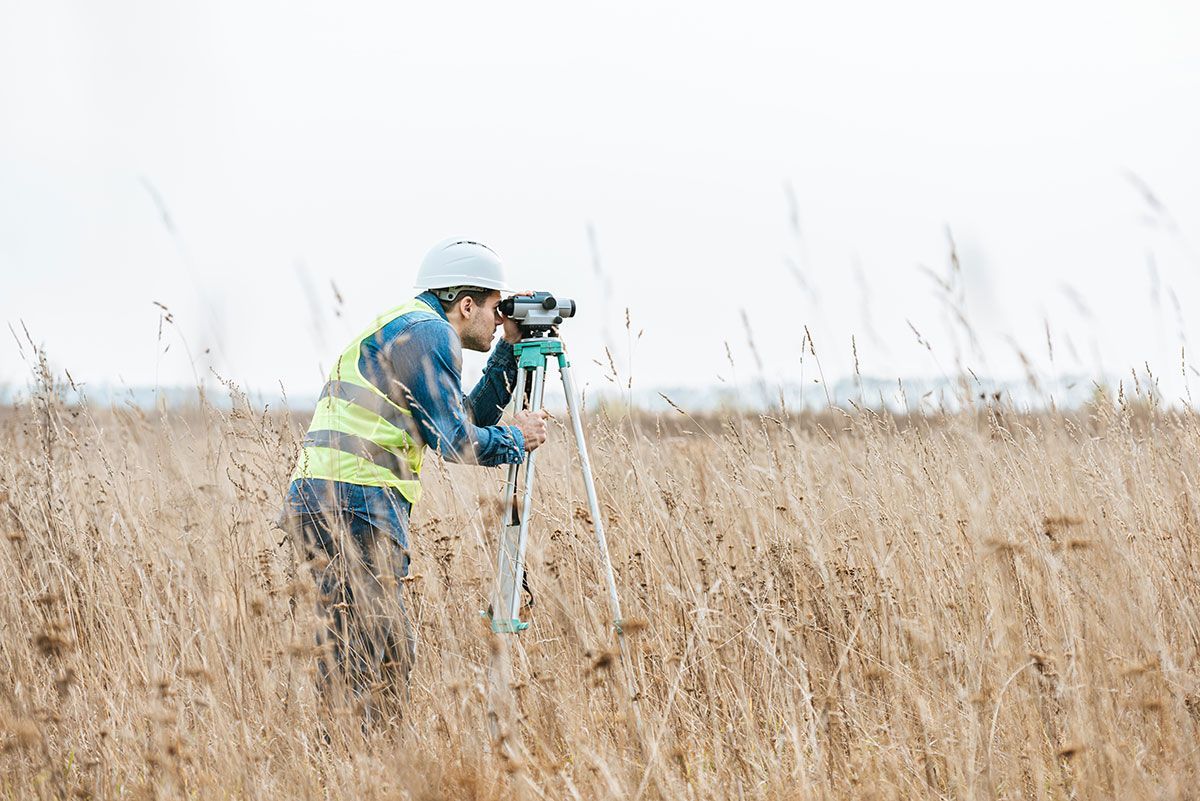 Géomètre qui procède à des relevés topographiques sur le terrain