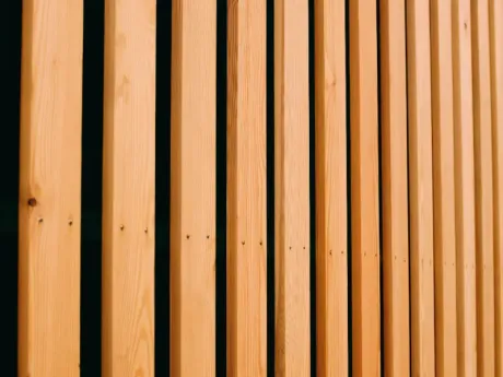 Primer plano de listones verticales de madera de color marrón claro con estrechas hendiduras negras.