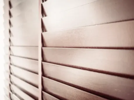Primer plano de persianas beige con líneas de luz y sombra inclinadas.