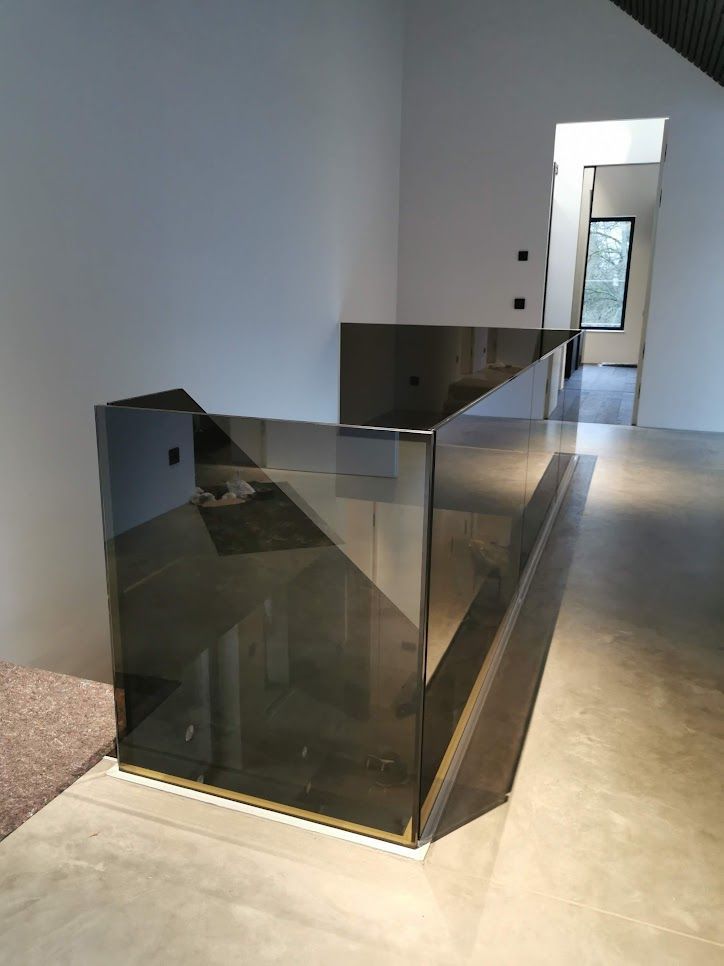 Treppengeländer aus Rauchglas in einem modernen Zuhause. Neutrale Farben, schlankes Design.