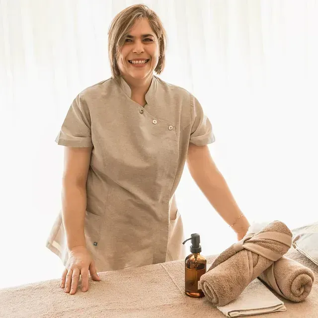 Una mujer está de pie junto a una mesa con toallas y una botella de jabón.