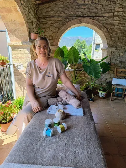 Una mujer está sentada en una mesa de masajes en un porche.