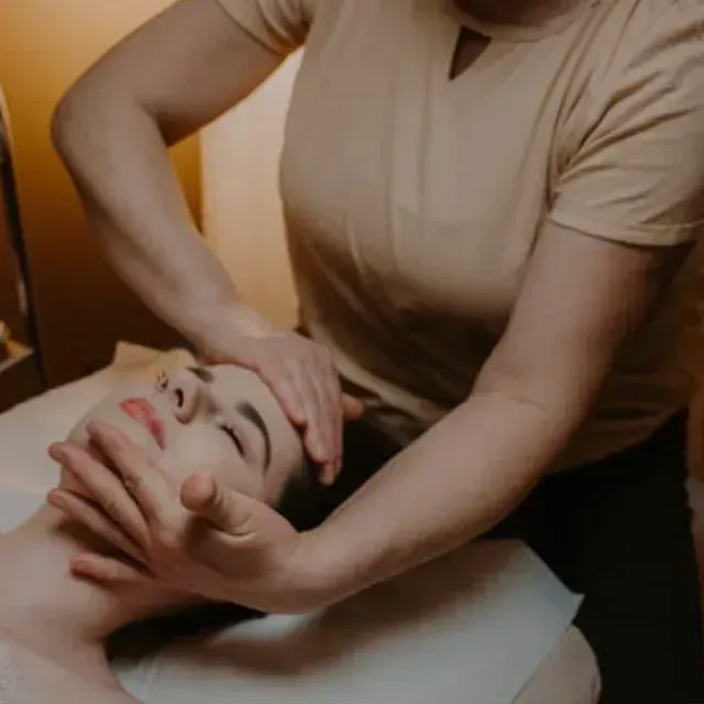 Una mujer está dando un masaje en la cara de una mujer.