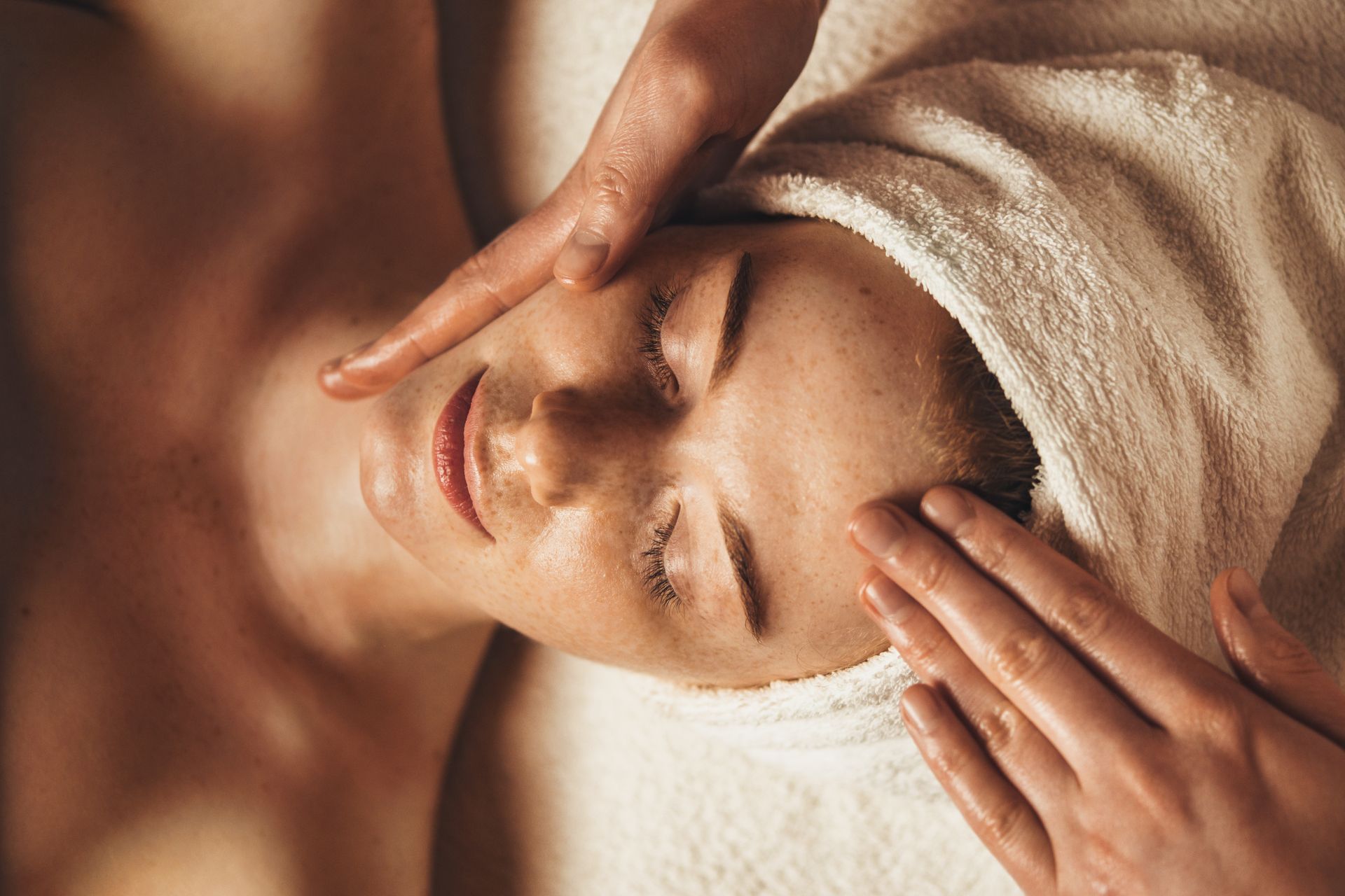 Personne recevant un massage du visage avec une serviette enroulée autour de la tête