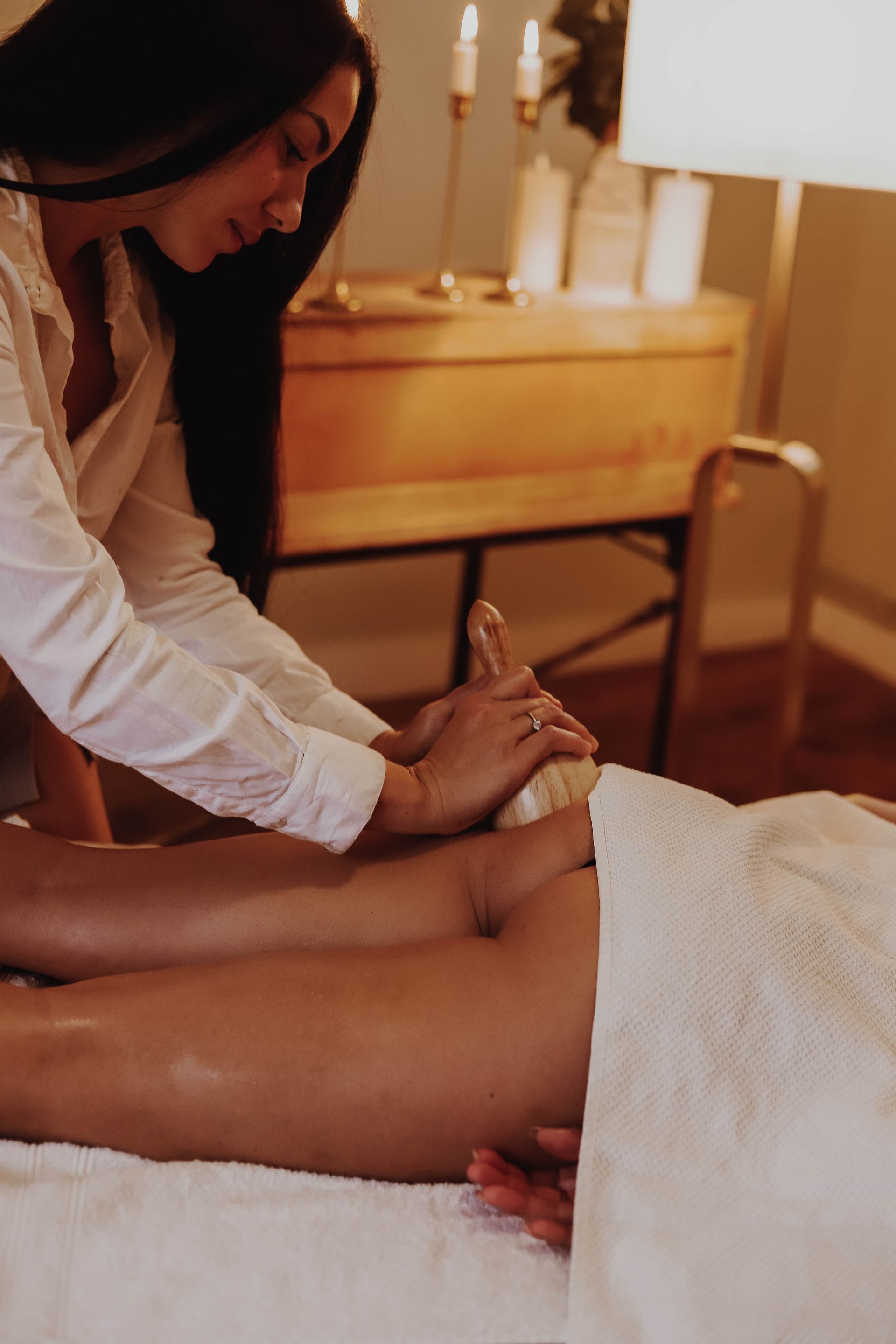 Une masseuse travaille sur le dos d'une cliente dans une salle de spa chaleureuse éclairée aux chandelles.