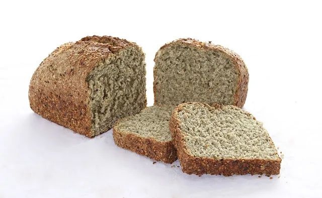 Una hogaza de pan se corta en rebanadas sobre una superficie blanca.