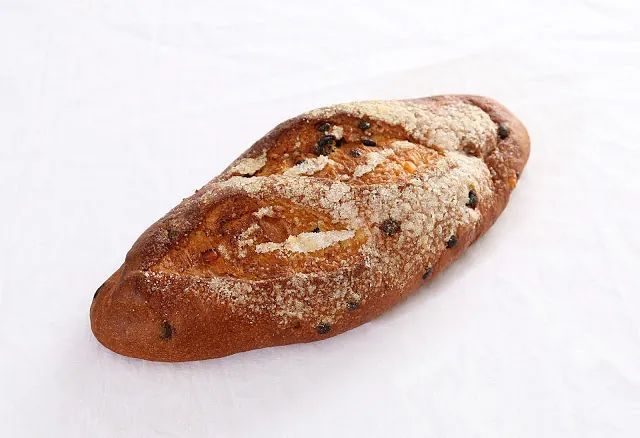 Una hogaza de pan reposa sobre una superficie blanca.