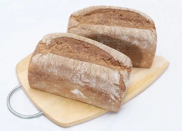 Dos hogazas de pan están colocadas sobre una tabla de cortar de madera.