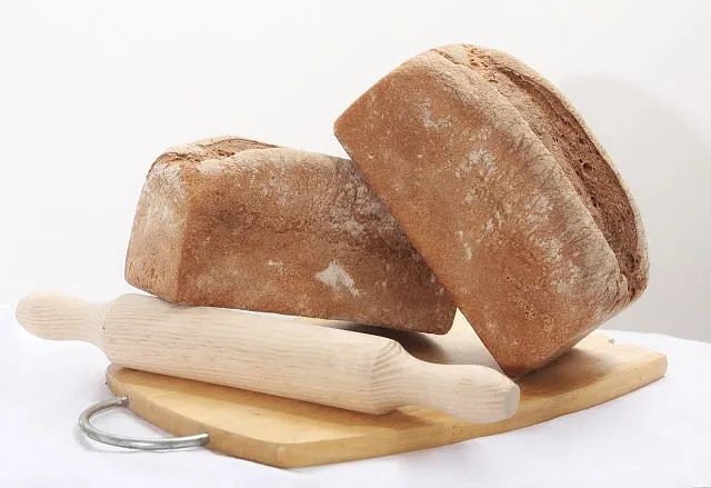 Tres panes y un rodillo sobre una tabla de cortar de madera