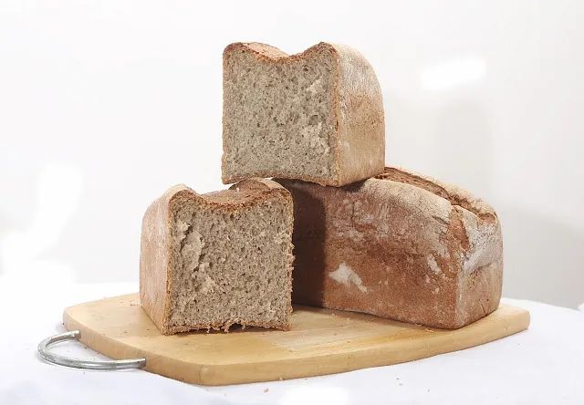Tres hogazas de pan se apilan una encima de otra sobre una tabla de cortar de madera.