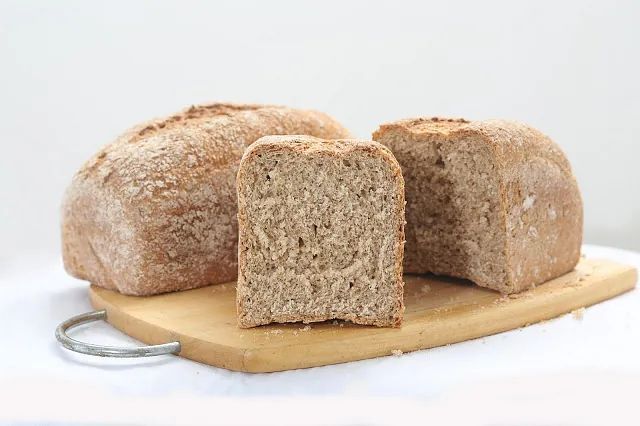 Una hogaza de pan reposa sobre una tabla de cortar de madera.