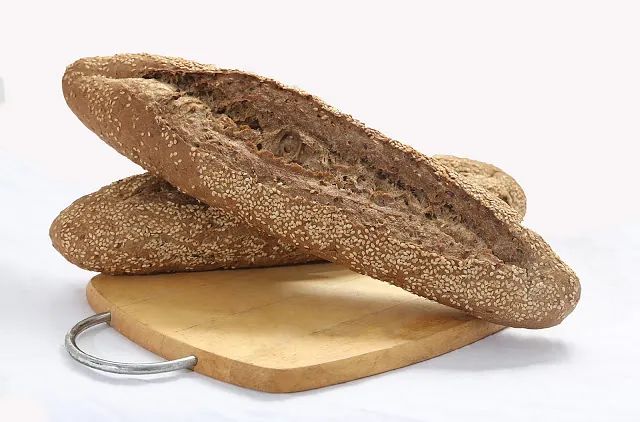 Dos hogazas de pan están colocadas encima de una tabla de cortar de madera.