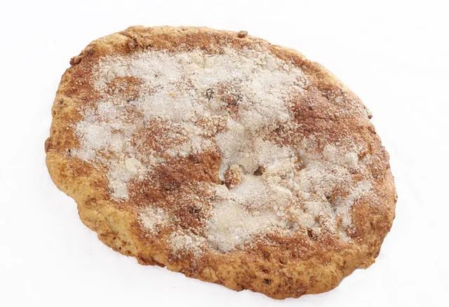 Una galleta con azúcar en polvo encima sobre un fondo blanco.