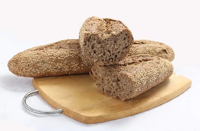 Tres hogazas de pan están colocadas sobre una tabla de cortar de madera.