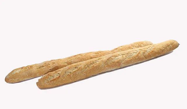 Dos baguettes están colocadas una encima de otra sobre una superficie blanca.