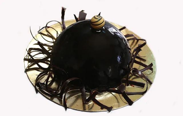 Un pastel de chocolate en un plato con virutas de chocolate encima.