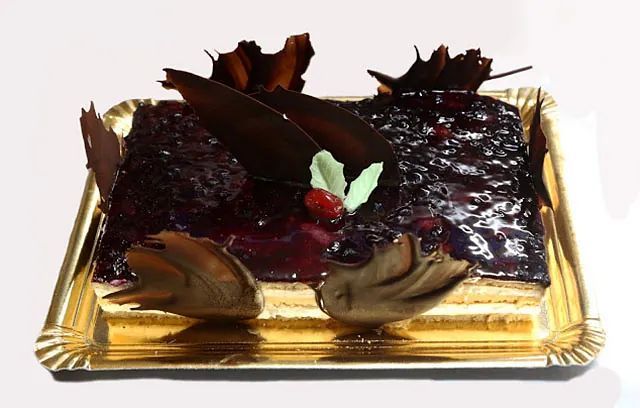 Un pastel con bayas y chocolate en una bandeja dorada.