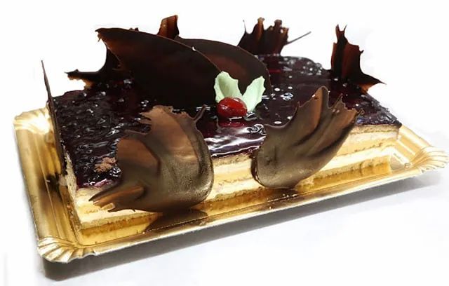 Un pastel de chocolate con una cereza encima está en un plato de papel.