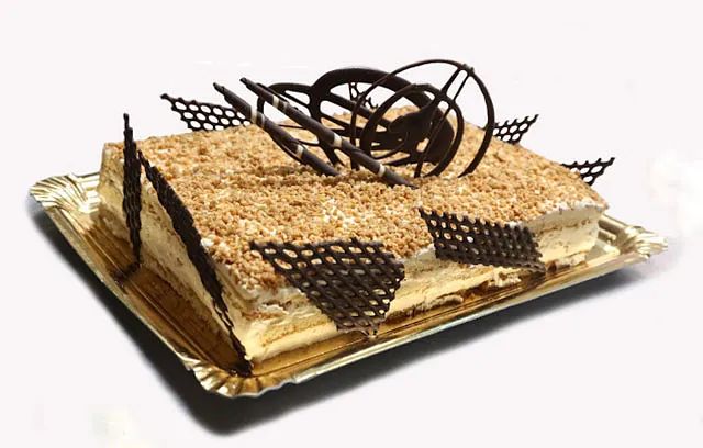 Un pastel con decoraciones de chocolate está en una bandeja de papel.