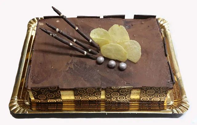 Un pastel de chocolate reposa sobre una bandeja de oro.