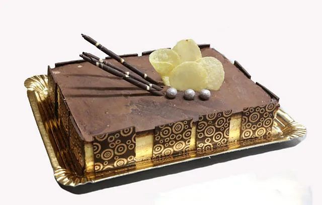 Un pastel de chocolate está en una bandeja de papel sobre un fondo blanco.