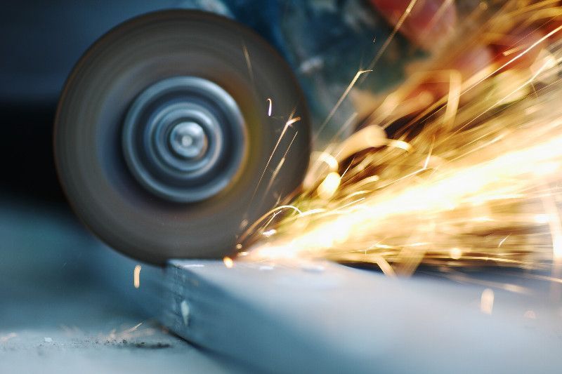 Amoladora angular cortando metal, produciendo chispas.