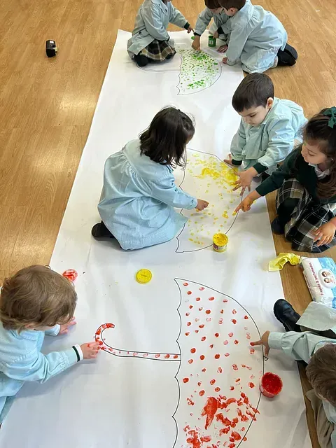 Un grupo de niños está sentado en el suelo pintando un paraguas.