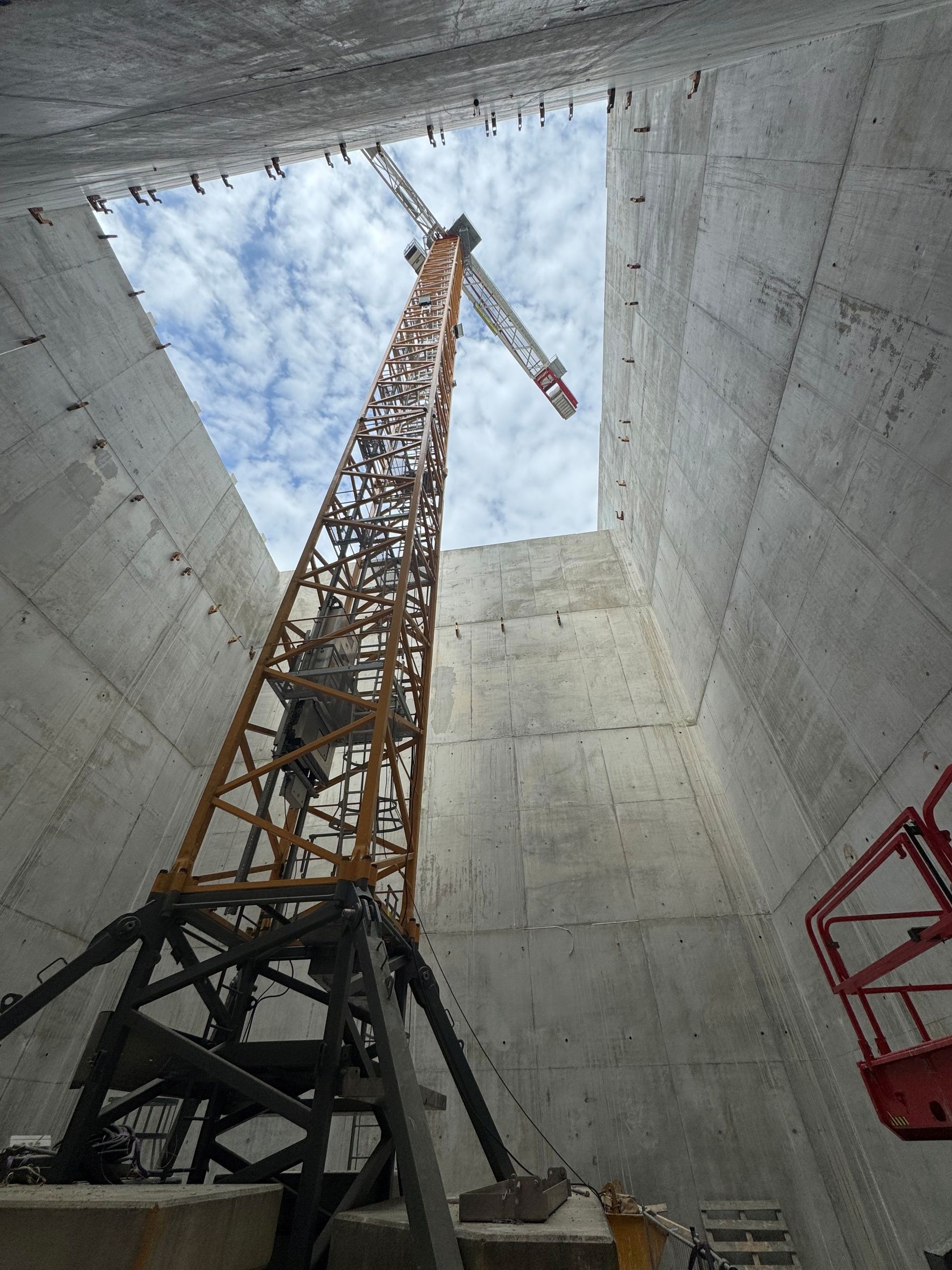 Grue de chantier de grande hauteur à l'intérieur d'un puits en béton, vue vers le ciel.