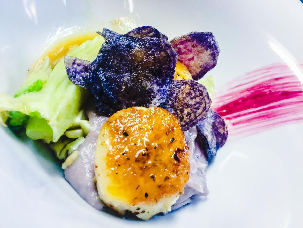 Eine Nahaufnahme von einem Teller mit Essen mit violetten Kartoffeln