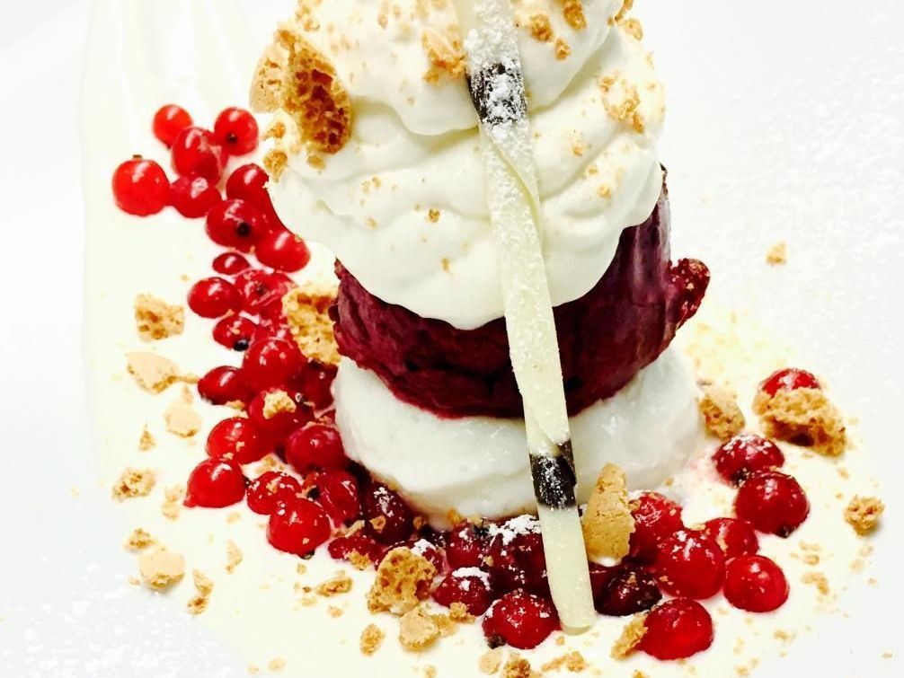 Ein Dessert mit Schlagsahne und Beeren auf einem weißen Teller