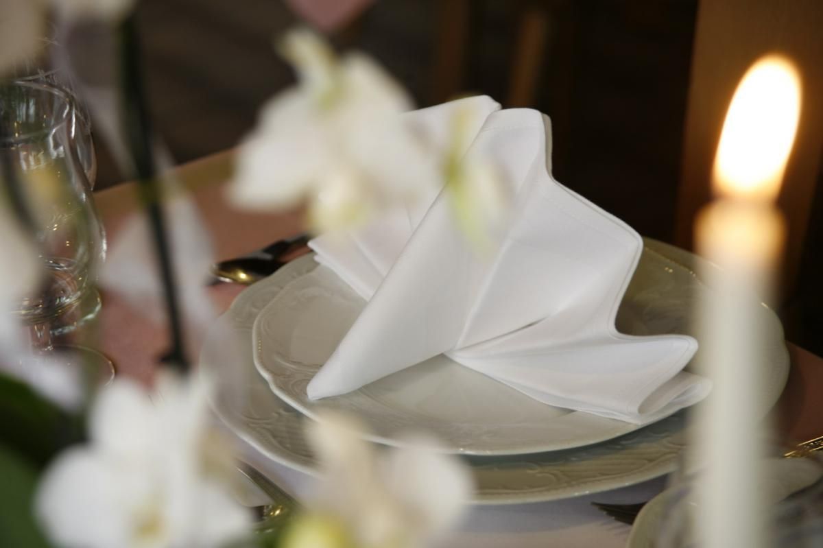 Eine Tischdekoration mit Tellern, Servietten, Kerzen und Blumen.