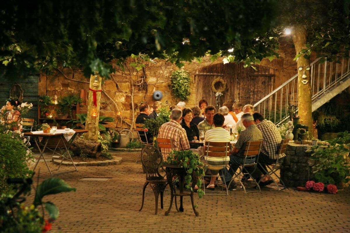 Eine Gruppe von Leuten sitzt in einem Biergarten um einen Tisch.