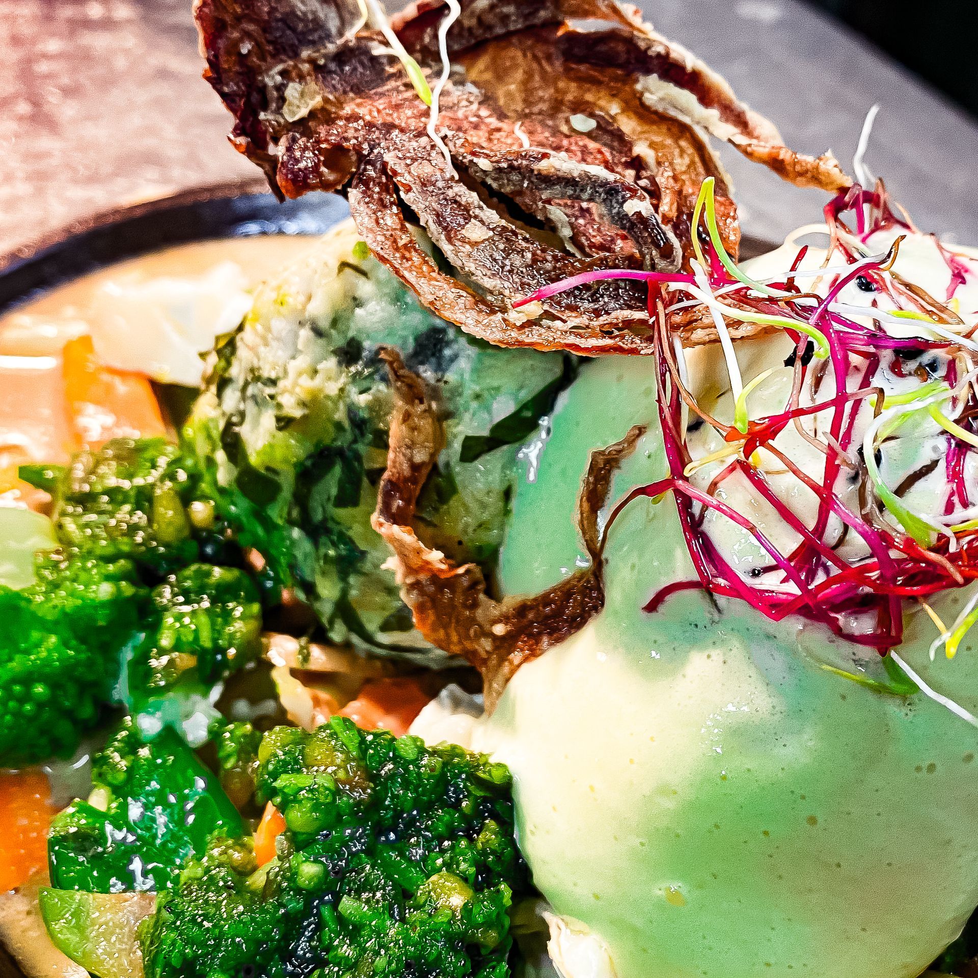 Eine Nahaufnahme eines Tellers mit Gemüse und Soße auf einem Tisch.