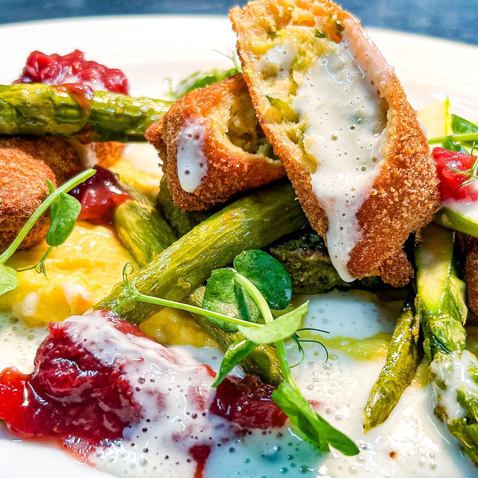 Frittiertes, Spargel und Soße auf einem Teller; ein Gourmetgericht.