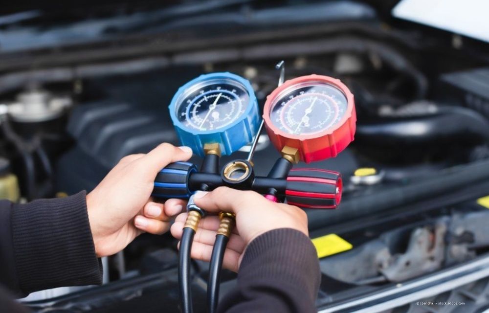 Mit behandschuhten Händen reparieren Werkzeuge die Motorverkabelung im Motorraum eines Autos.