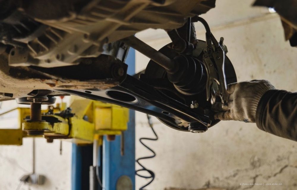 Autowerkstatt mit mehreren Autos auf Hebebühnen und Mechanikern, die unter offenen Motorhauben arbeiten.