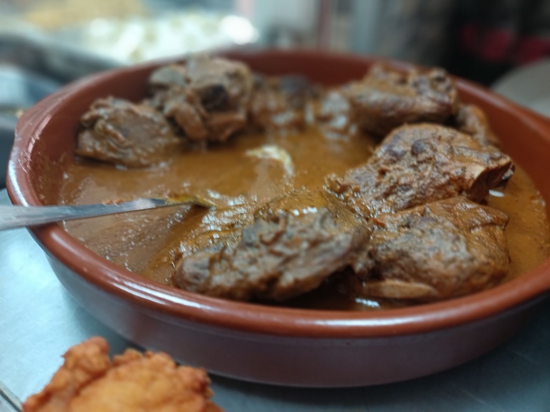 Un tazón de carne y salsa con una cuchara dentro.