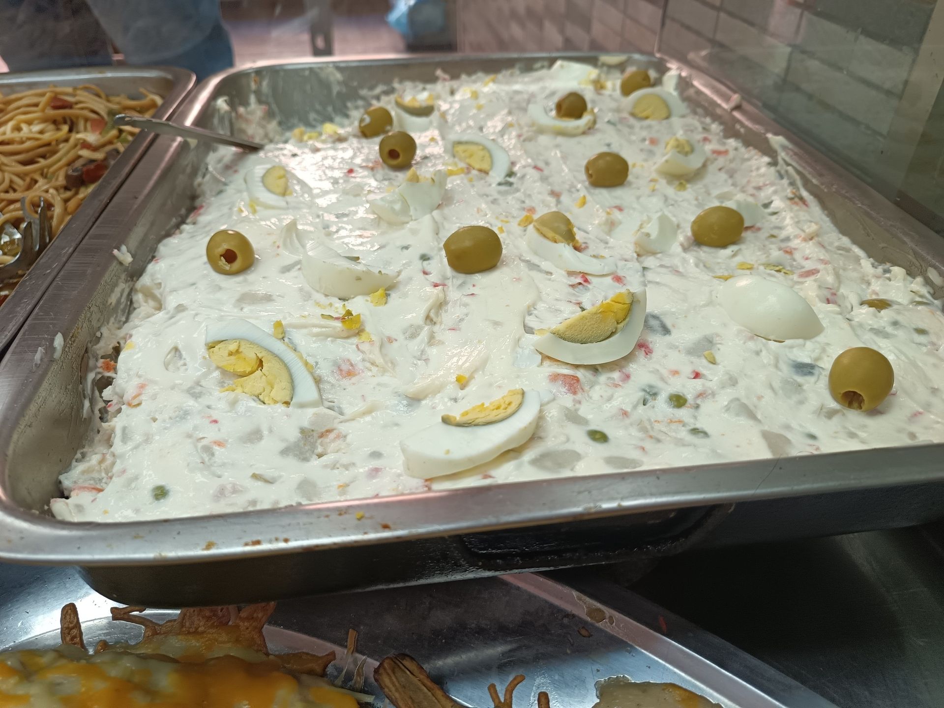 Una bandeja de comida con huevos, aceitunas y otras verduras sobre una mesa.