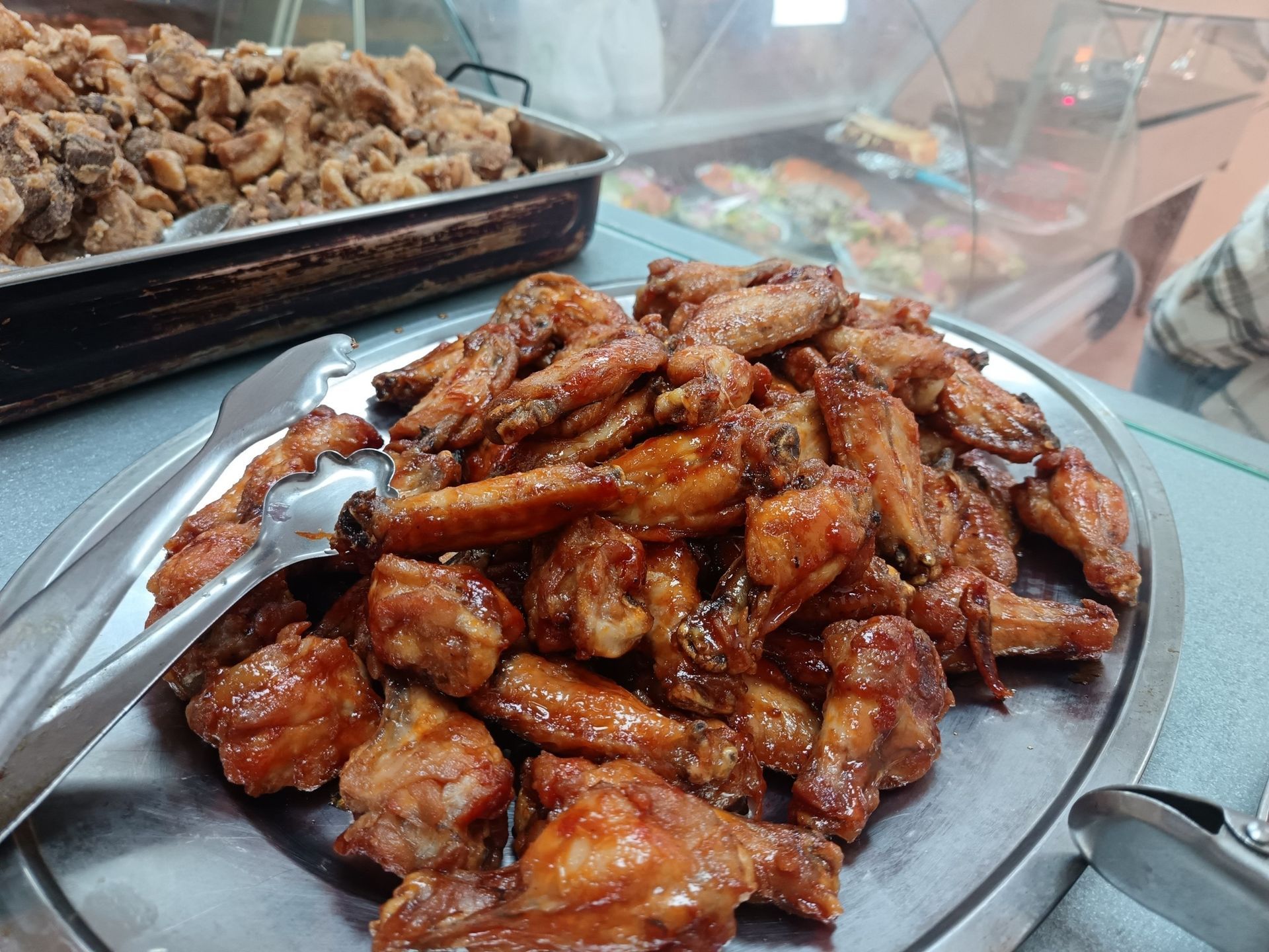 Un plato de alitas de pollo con pinzas encima.