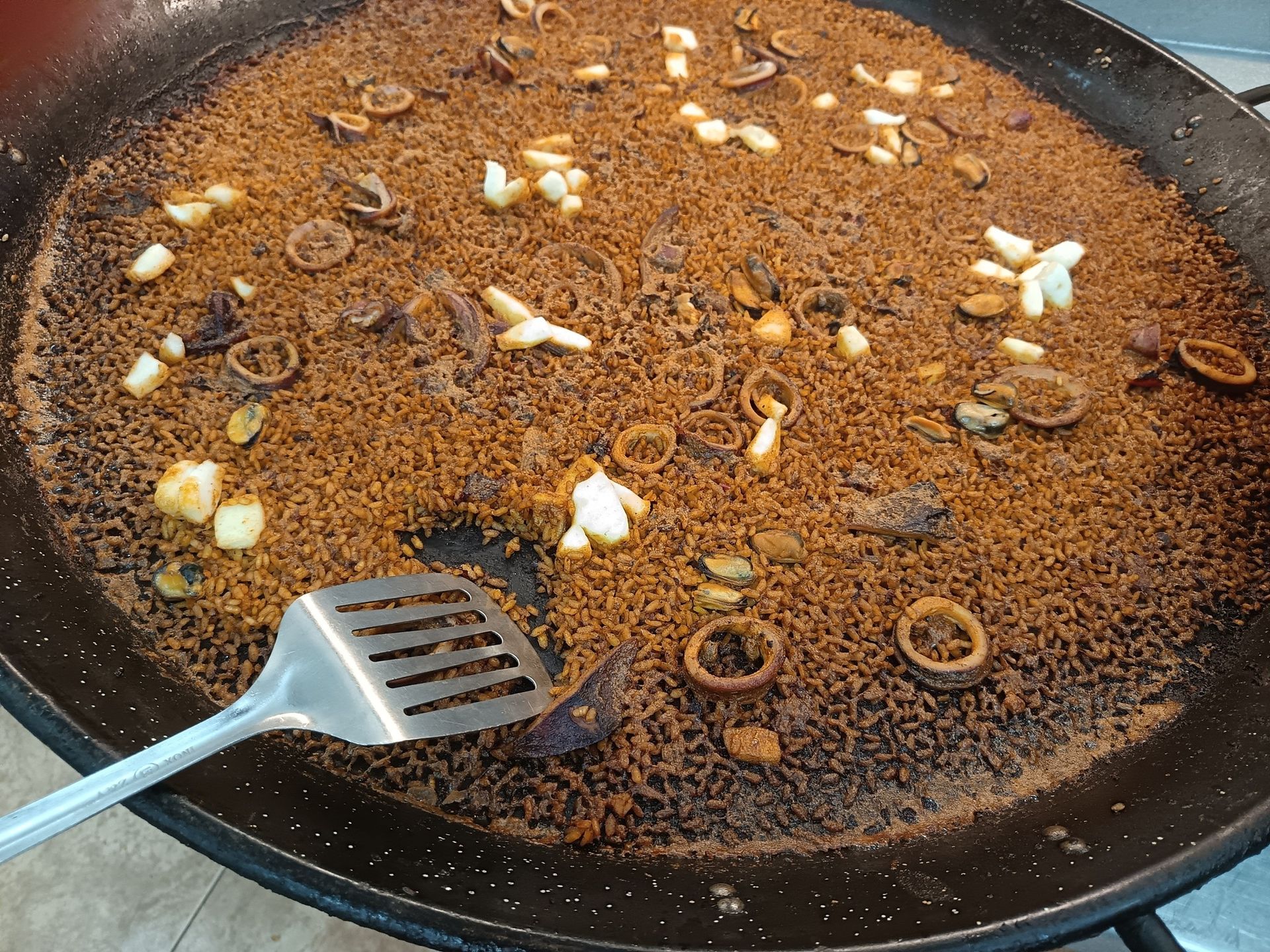 Una sartén con comida y una espátula dentro